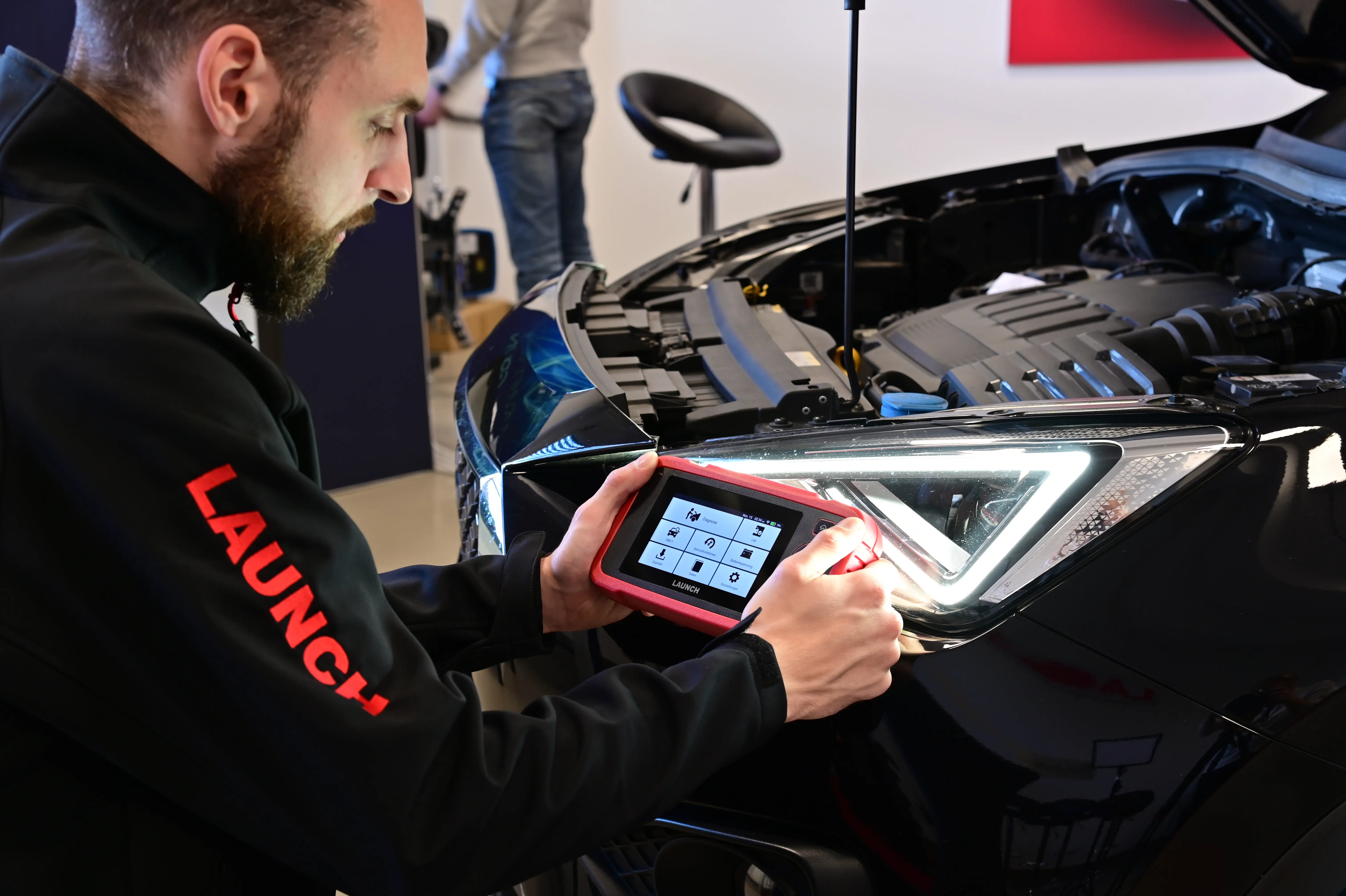 Technician using a DIY car diagnostic tool to diagnose vehicle faults in a workshop.